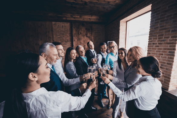 a corporate team celebrating and clinking wine glasses